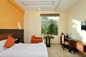 a bedroom with a bed and a desk and a window at Hotel Bhaskar in Jaipur