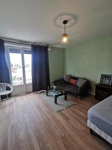 een woonkamer met een bank en een bed bij Appartement, charmant type F1 37m2 vue dégagée, in Commentry