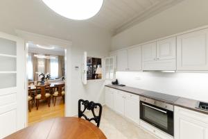 a kitchen with white cabinets and a table and a dining room at Castellano Hotel & Suites in Nafplio