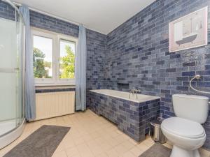 een blauwe betegelde badkamer met een toilet en een bad bij House Managers - Vintage Sopot in Sopot
