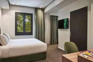 1 dormitorio con cama, escritorio y ventana en NLH KERAMEIKOS - Neighborhood Lifestyle Hotels, en Atenas