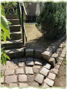 a garden with a stone walkway with a tree and stairs at Ferienwohung zum Bernerhof in Lindenberg