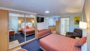 a hotel room with two beds and a chair at Motel Carnarvon in Roma