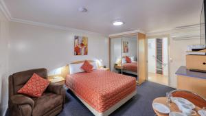 a bedroom with a bed and a couch and a chair at Motel Carnarvon in Roma