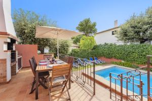 a patio with a table and an umbrella next to a pool at Villa Ramis by JS Villas in Cala de Sant Vicenc