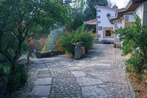 a stone walkway in front of a house with trees at Casa Rural La Central-Peñagorda in El Barco de Ávila