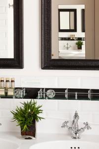 La salle de bains est pourvue d'un lavabo avec un miroir à cadre noir et un miroir. dans l'établissement Hôtel Sainte-Beuve, à Paris