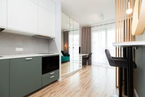 uma cozinha com armários brancos e uma mesa com cadeiras em Cozy apartment Kazimierza 48, Wola em Varsóvia