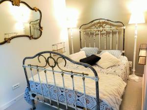een slaapkamer met een metalen bed met een spiegel aan de muur bij L'éléphant Blanc de ConcarnOLoc in Concarneau