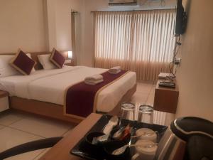 une chambre d'hôtel avec un lit et une table dans l'établissement Vijay Inn by Unicorn, à Krishnagiri