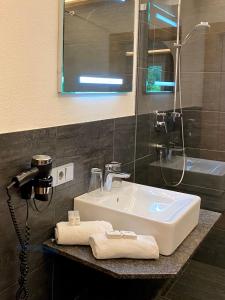 uma casa de banho com um lavatório, um chuveiro e um espelho. em Almhof Kitzlodge - Alpine Lifestyle Hotel em Kirchberg in Tirol
