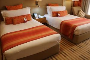 Habitación de hotel con 2 camas con almohadas de color naranja en Crowne Plaza Sohar, an IHG Hotel, en Sohar