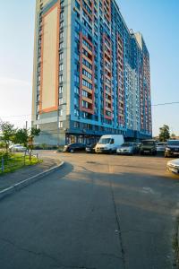 un grande edificio con auto parcheggiate in un parcheggio di Kvartirkoff na Bogatirskaya 6a, 17 floor a Kiev