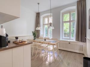 a kitchen with white cabinets and a table and chairs at limehome Berlin Lottumstraße 4 in Berlin