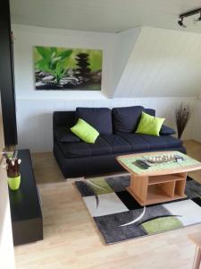 a living room with a black couch and a coffee table at Ferienwohnung "Bittner" in Thomsdorf