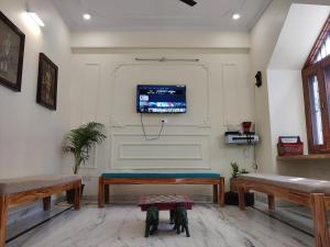 a living room with a bench and a tv on the wall at The Karauli Villa by Le Pension Stays in Jaipur
