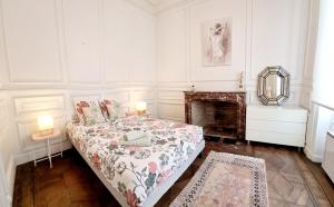 Dormitorio blanco con cama y chimenea en Maison spacieuse avec balcon sur les remparts, en Angulema