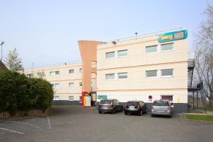 ein Gebäude mit auf einem Parkplatz geparkten Autos in der Unterkunft hotelF1 Nemours in Nemours