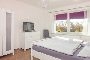 a white bedroom with a bed and a tv at Mia in Dahme