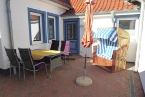 eine Terrasse mit einem Tisch, Stühlen und einem Sonnenschirm in der Unterkunft Ferienhaus Anke in Heiligenhafen