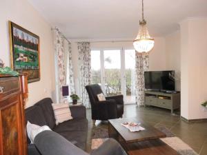 ein Wohnzimmer mit einem Sofa, Stühlen und einem TV in der Unterkunft Ferienhaus Anke in Heiligenhafen