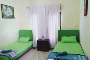 Duas camas verdes num quarto com uma janela em Quattrick Dee Homestay Mitra RedDoorz em Manokwari