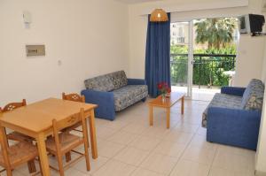 a living room with blue furniture and a table and chairs at Mariela Hotel Apartments in Polis Chrysochous