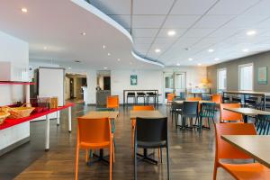 un restaurante con mesas y sillas y una cocina en hotelF1 Igny Massy TGV, en Igny