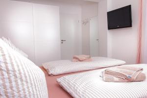 a room with two beds and a tv on a wall at M4 - Apartmenthaus Marienburger Str 4 - FERIENDOMIZIL HOLLICH in Grömitz