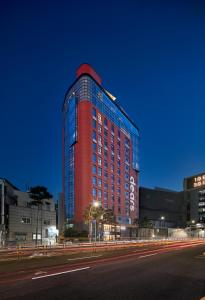 Un grand bâtiment rouge avec des lumières sur son côté dans l'établissement Dears Myeongdong, à Séoul