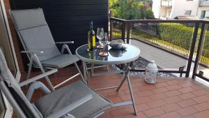 eine Terrasse mit einem Tisch, 2 Stühlen und Weingläsern in der Unterkunft Deichkrone App 11 in Grömitz