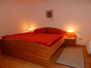 een slaapkamer met een houten bed met rode lakens en 2 lampen bij Haus Carmesin in Eckernförde