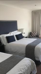 una habitación de hotel con 2 camas y una silla en Aaron Glen Apartments, en Edimburgo