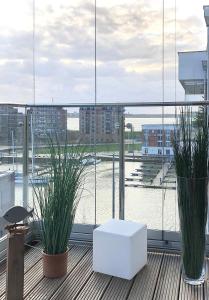 uma varanda com dois vasos de plantas e uma mesa branca em Port Marina "Schlagseite" em Bremerhaven