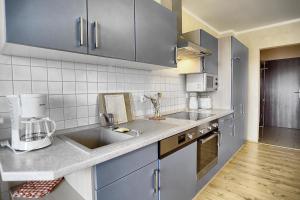 uma cozinha com armários azuis e um lavatório em Robbe FW 4 em Zingst