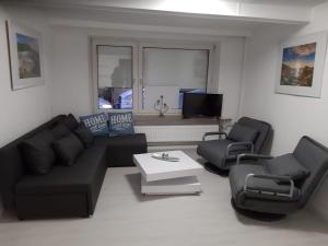 uma sala de estar com um sofá preto e duas cadeiras em Ferienhaus Heide Zentrum em Heide