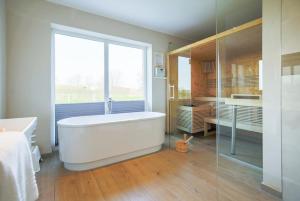 a bathroom with a large tub and a glass shower at Ferienhof Büdlfarm - Wohlfühlhütte - 51652 in Sahrensdorf