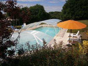 una piscina con sombrilla naranja y silla en Le POULAILLER, en Mareuil-sur-Lay