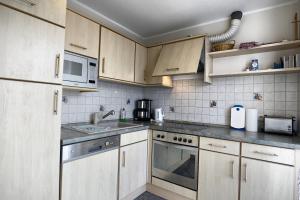 a kitchen with white cabinets and a sink and a microwave at Nele, Whg 3 in Zingst