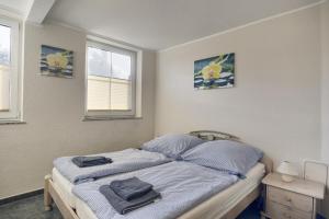 a bedroom with a bed with blue sheets and two windows at Nele, Whg 3 in Zingst