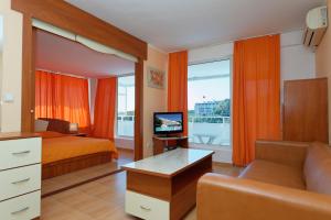 a bedroom with a bed and a tv and a couch at Hotel Pliska All inclusive in Golden Sands