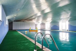 uma grande piscina com pisos e tectos verdes em Penuwch Boathouse- Lakeside rural cottage ideal for families with indoor heated pool em Carmarthen