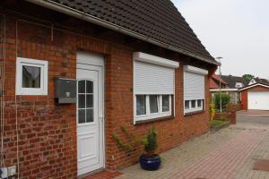 a brick house with a white door and two windows at Ferienwohnung Petersen I in Büdelsdorf