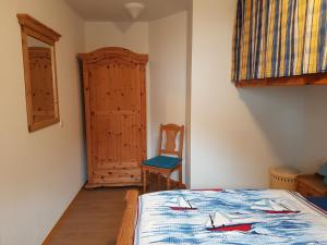 sypialnia z łóżkiem z niebieską kołdrą i krzesłem w obiekcie Haus Weidenhof App 1 w Prerowie