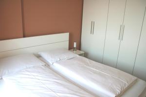 uma cama branca num quarto com armários brancos em ancora Marina Haus 1 Nr 09, Typ 3 em Neustadt in Holstein