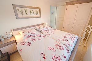 a bedroom with a white bed with red flowers on it at Les Belles, Haus Davide, FW Elegant FW 8 in Zingst