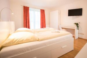 a white bedroom with a large bed with a window at Ostseebrise Reetdach 2 in Zingst