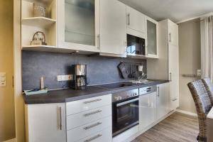 a kitchen with white cabinets and a stove top oven at Villa Vogelsang, Pier 6 in Zingst