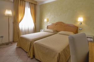 a hotel room with two beds and a window at Hotel La Perla in Àrbatax