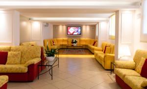 a waiting room with yellow couches and a tv at Hotel Imperia in Lido di Jesolo